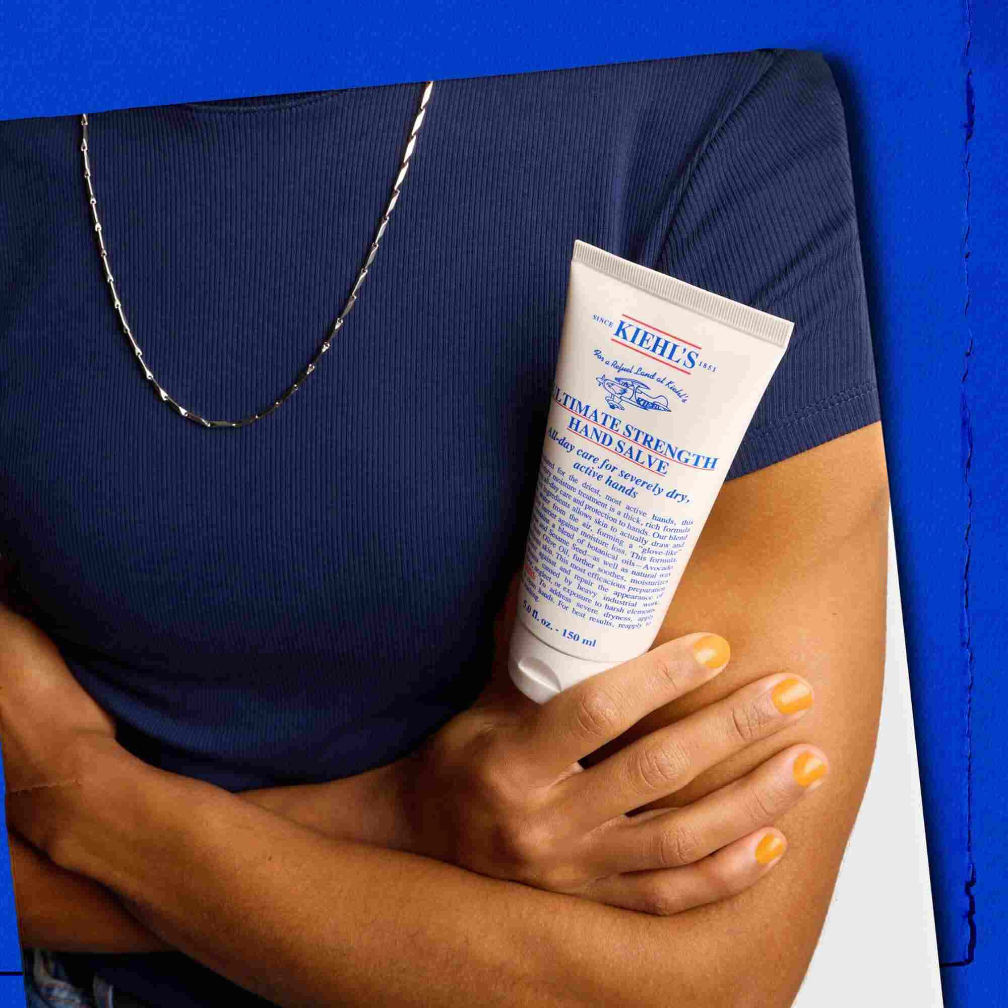 Model care ține un tub de Kiehl's Ultimate Strength Hand Salve
