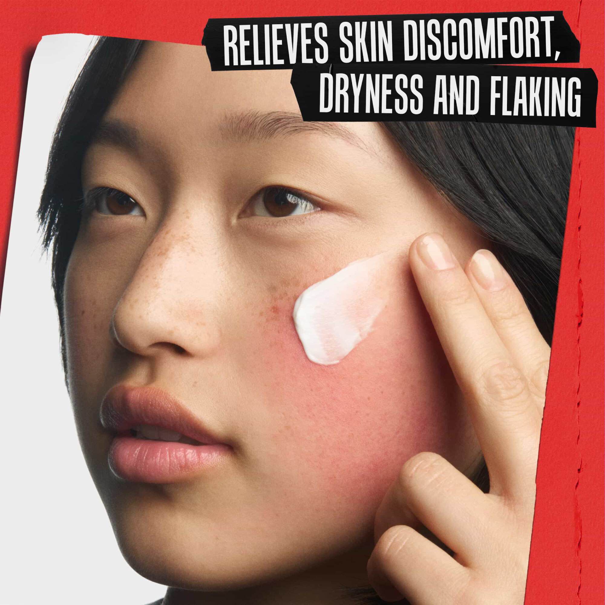 Gros-plan cu crema reparatoare aplicată pe un obraz iritat. Textul spune: AMELIOREAZĂ DISCONFORTUL CUTANAT, USKĂCIUNEA ȘI DESCUAMAREA.