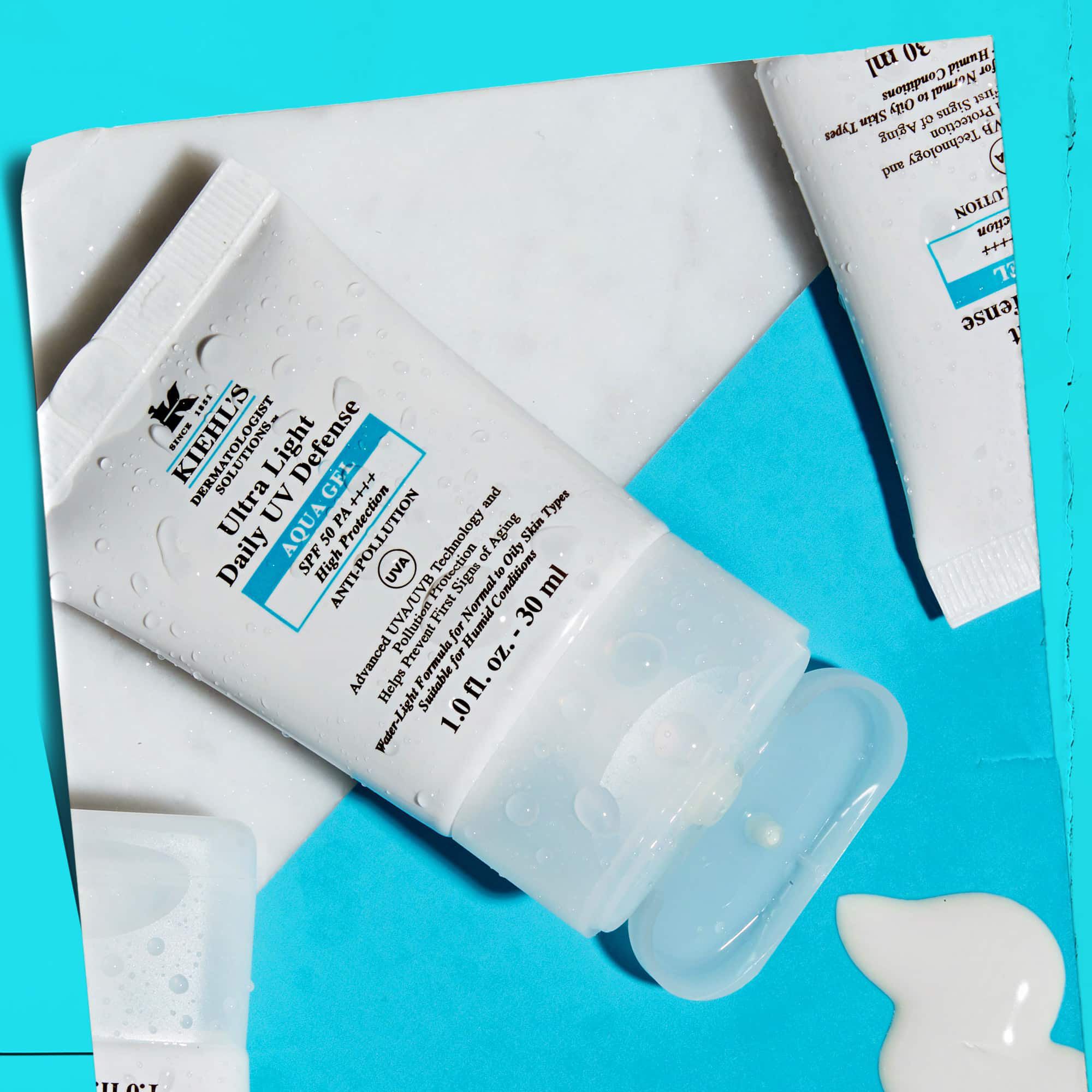 O așezare plană a mai multor tuburi Ultra Light Daily UV Defense Aqua Gel pe o suprafață de marmură, prezentand atractivitatea lor de stil de viață.