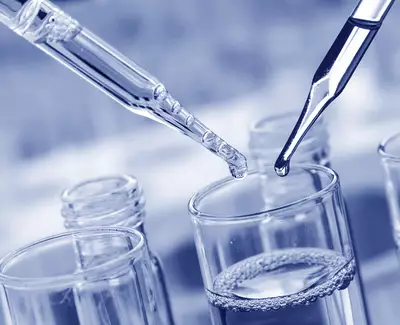 Two pipettes are positioned above a glass container filled with a clear liquid, with one pipette releasing a drop. The overall color tone is blue.