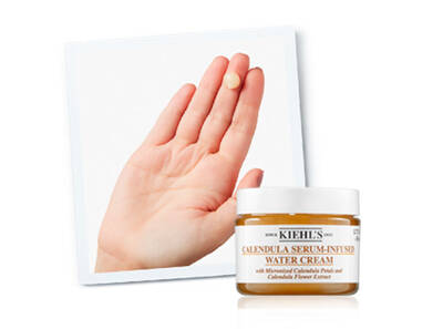 Crema hidratantă cu ser din flori de gălbenele, prezentată pe o palmă. Ambalajul este un borcan cu capac alb.