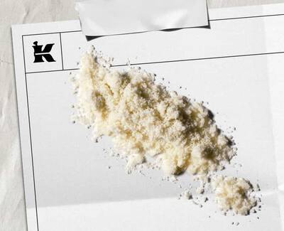 Pudră alb-gălbuie reprezentand fulgi de ovăz coloidal 1% pe o cearșafură albă cu un logo negru Kiehl's in colț.