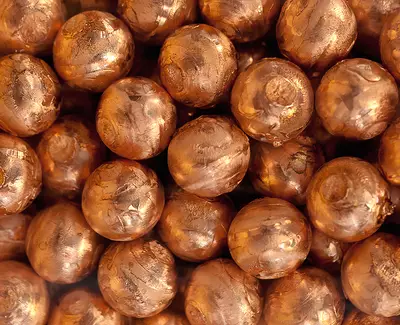 Close-up of a cluster of shiny, copper-colored spherical beads with a smooth surface.