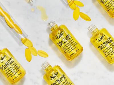 Flacoane de ser Kiehl's cu concentrat revitalizant, inconjurate de petale galbene pe un fundal alb.