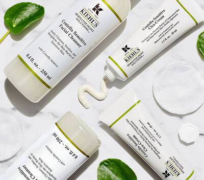 Produse de ingrijire facială Kiehl's: gel de curățare și cremă, pe un fundal alb, cu discuri demachiante.