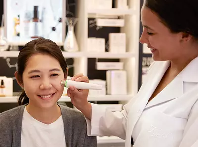 O specialistă aplică un dispozitiv de evaluare a pielii pe fața unei cliente intr-un salon Kiehl's.