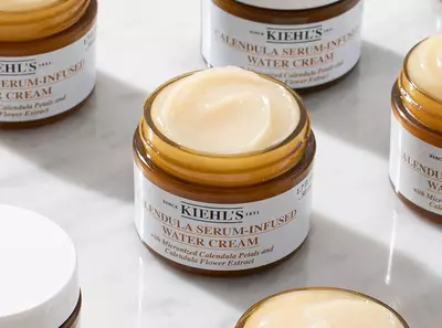 Crema hidratantă cu infuzie de serum de calendula, prezentată in borcane de sticlă pe o suprafață de marmură.