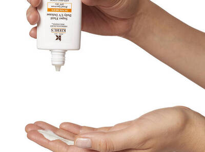 Mană aplicand cremă SPF Kiehl's pe palmă, pregătindu-se pentru hidratare și protecție solară.