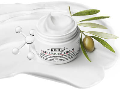 Cremă facială Kiehl's Ultra, cu textura cremă, insoțită de frunze de măslin și un fond alb cremos.